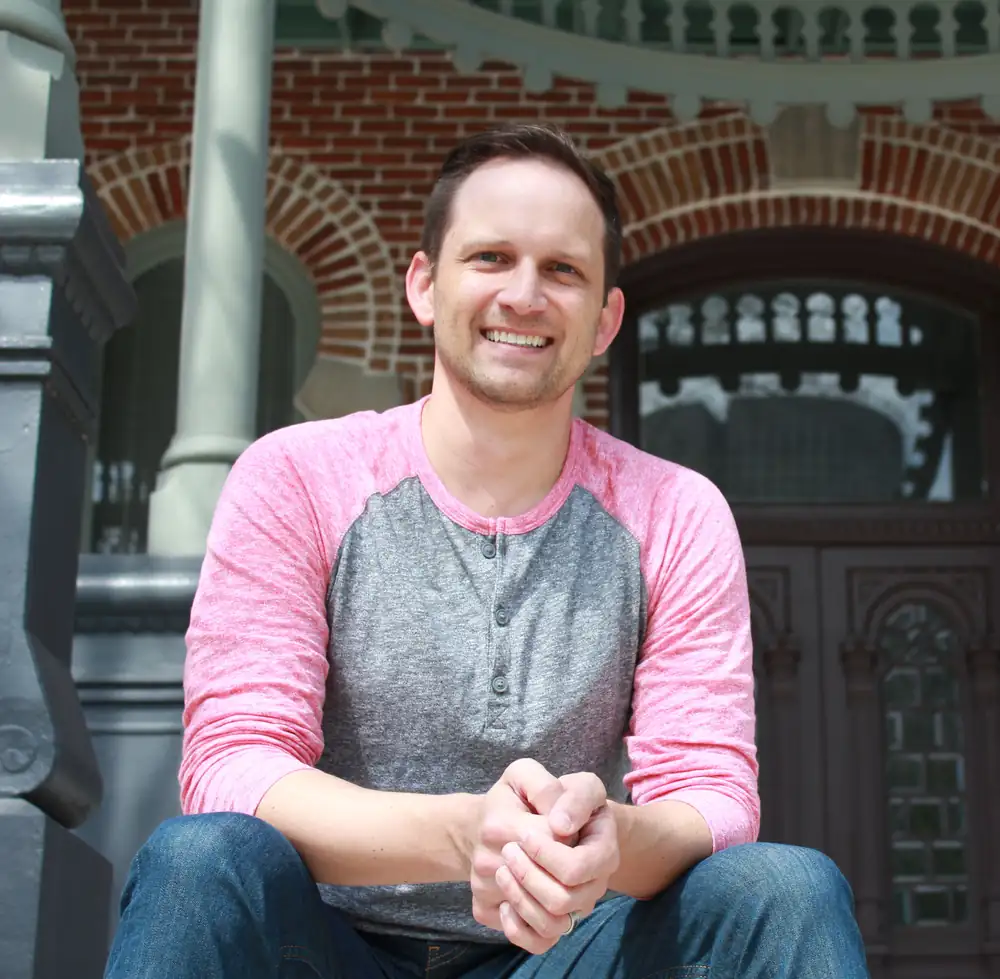 Andrew Tepen, media builder and digital operator, seated and smiling outside a brick building